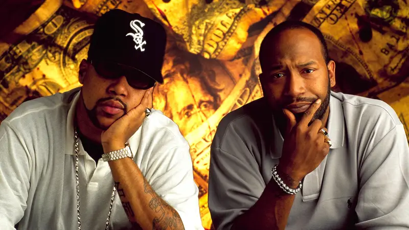 Pimp C and Bun B of UGK photographed together against a gold money backdrop