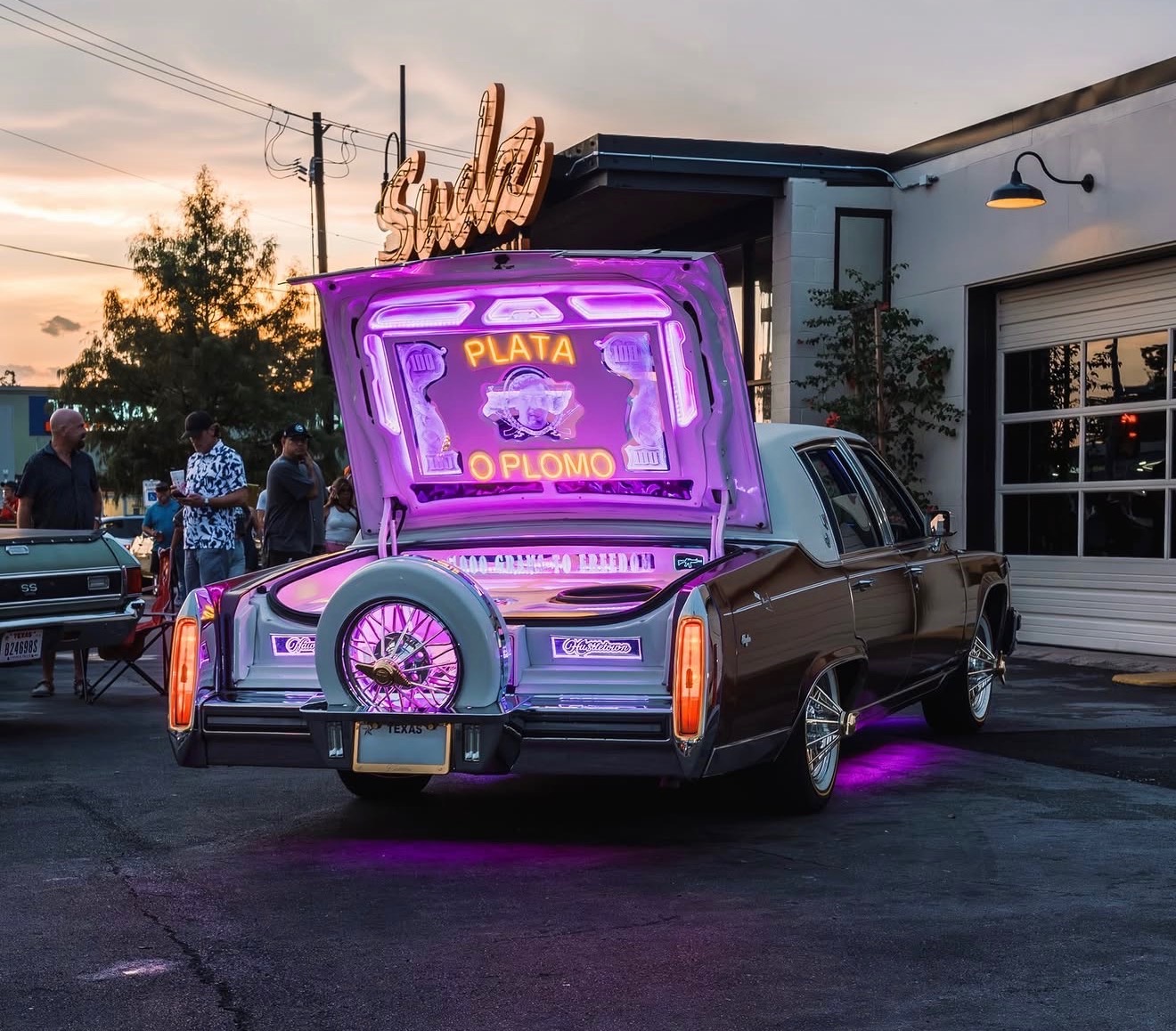 Neon-lit pop trunk with mirrored deck in a Cadillac