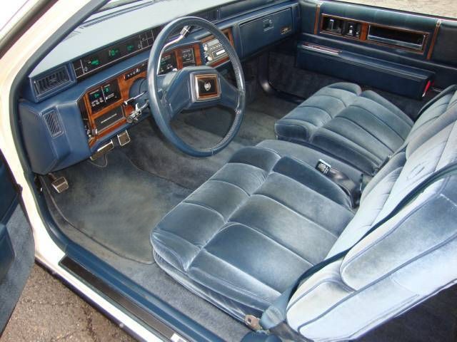 Cadillac Coupe DeVille interior with wood grain steering wheel, button-tufted seats and woodgrain dash