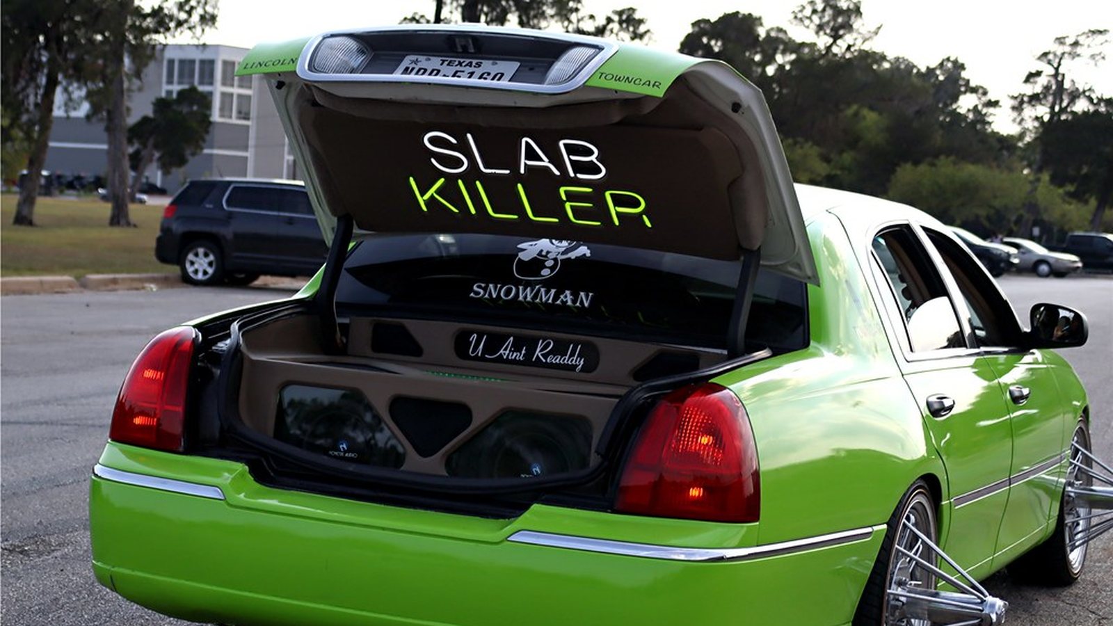 Lime green Lincoln Town Car slab with pop trunk and lettered speaker box at a Houston meet